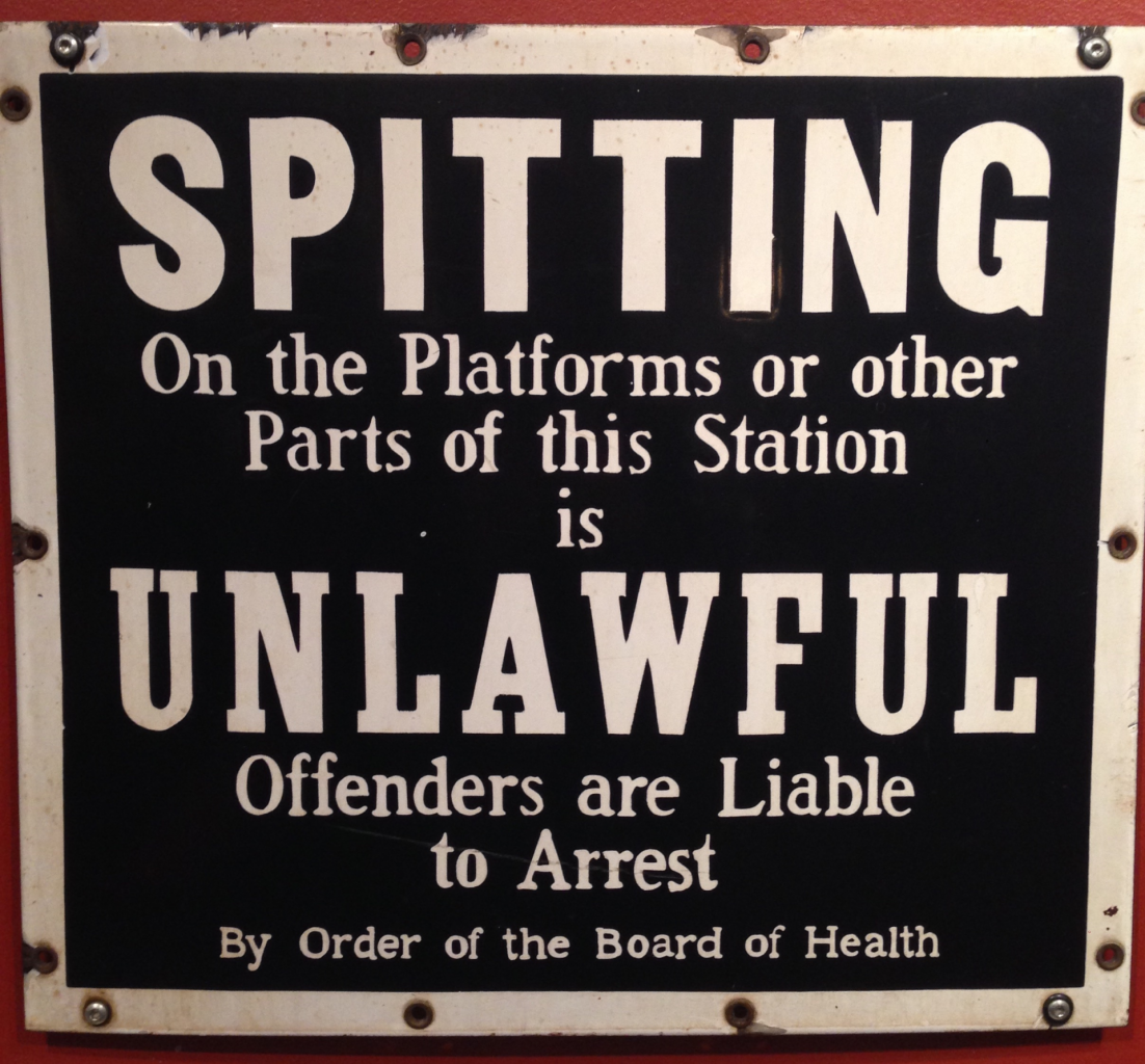 Subway sign that reads: Spitting on the Platforms or other parts of this Station is UNLAWFUL. Offenders are Liable to Arrest. By order of the Board of Health