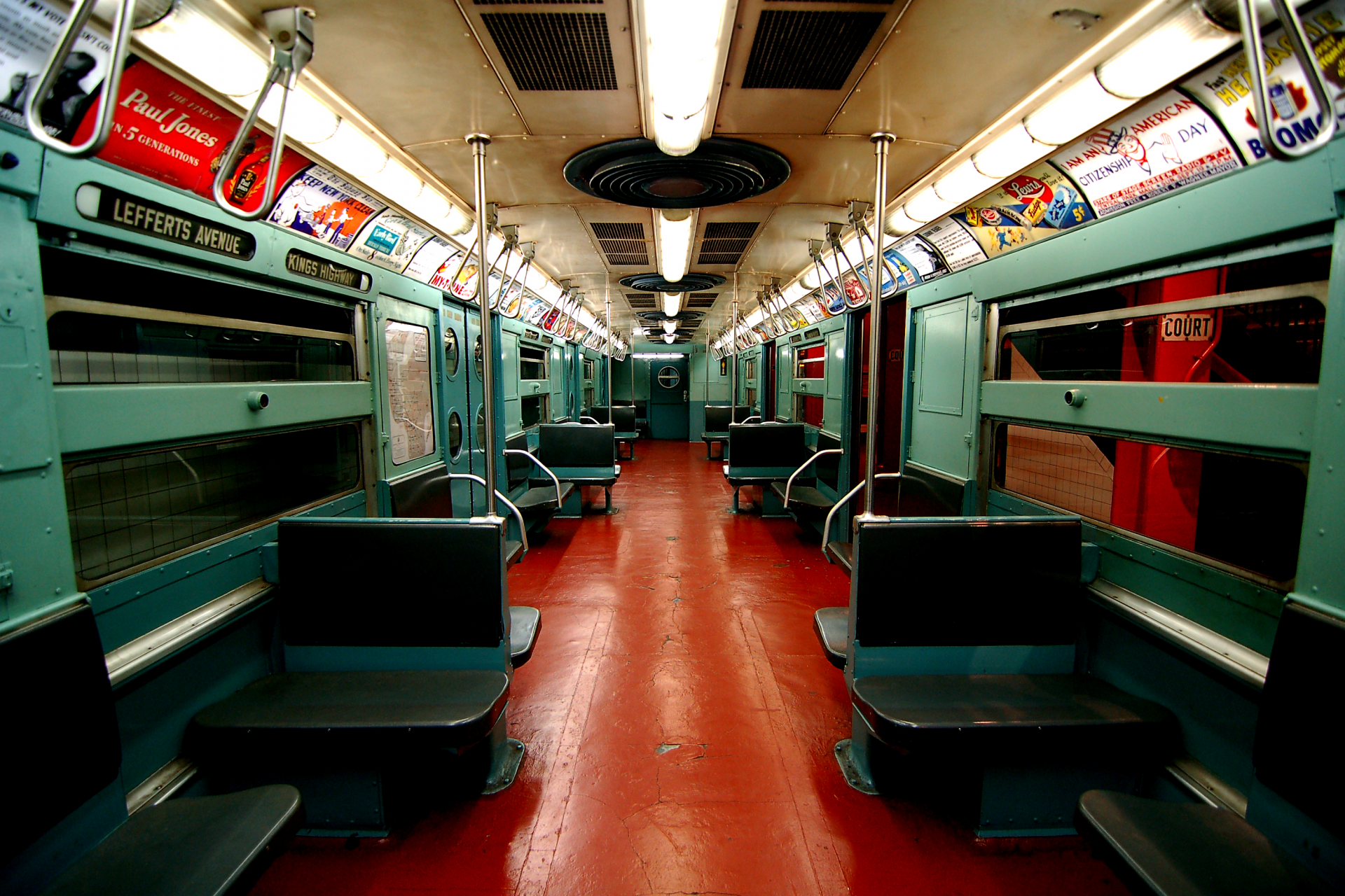 The inside of the R11 prototype subway car has red floors, grey plastic seats, and aqua green walls.