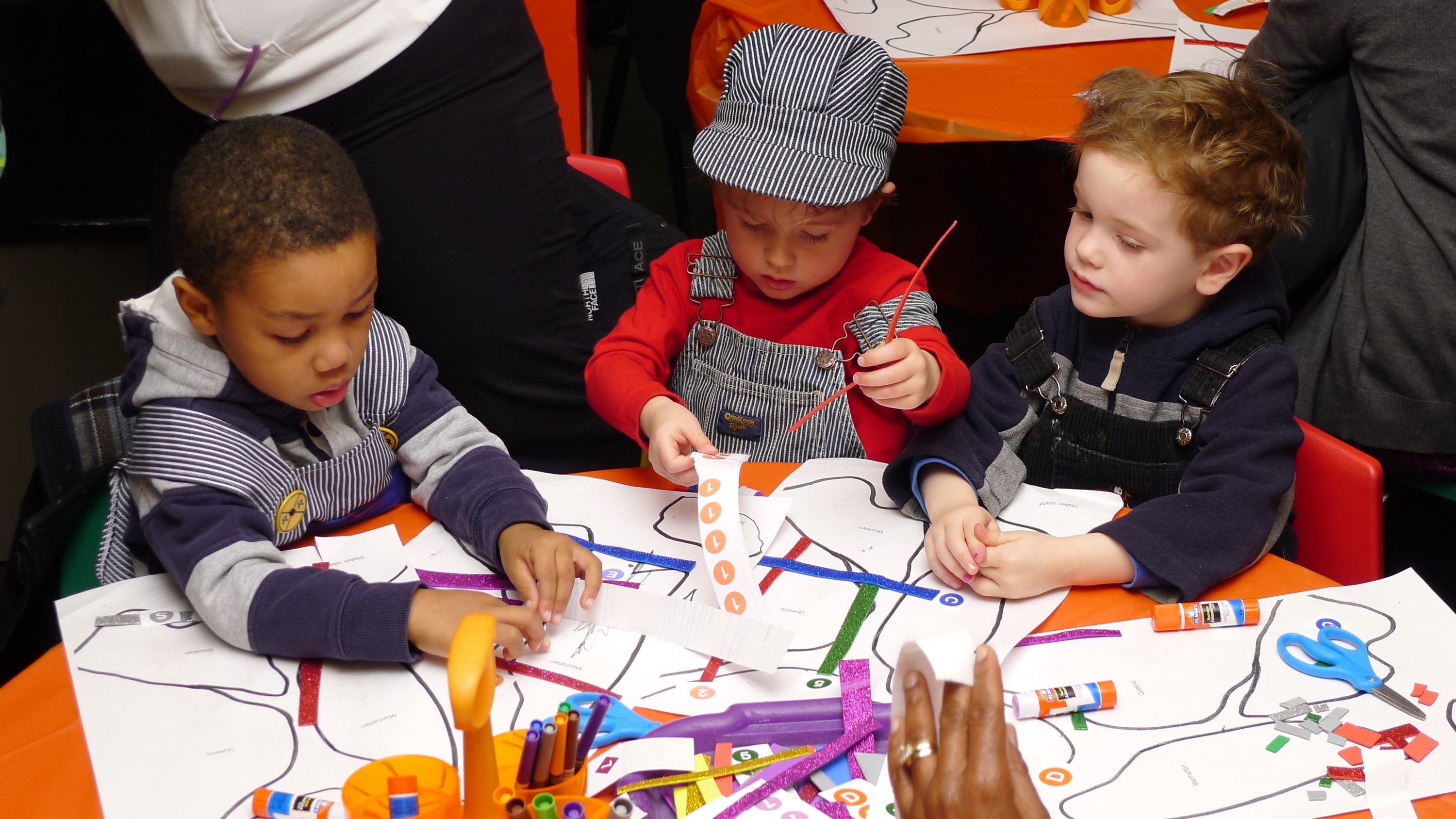 Three children at a table explore an art activity.