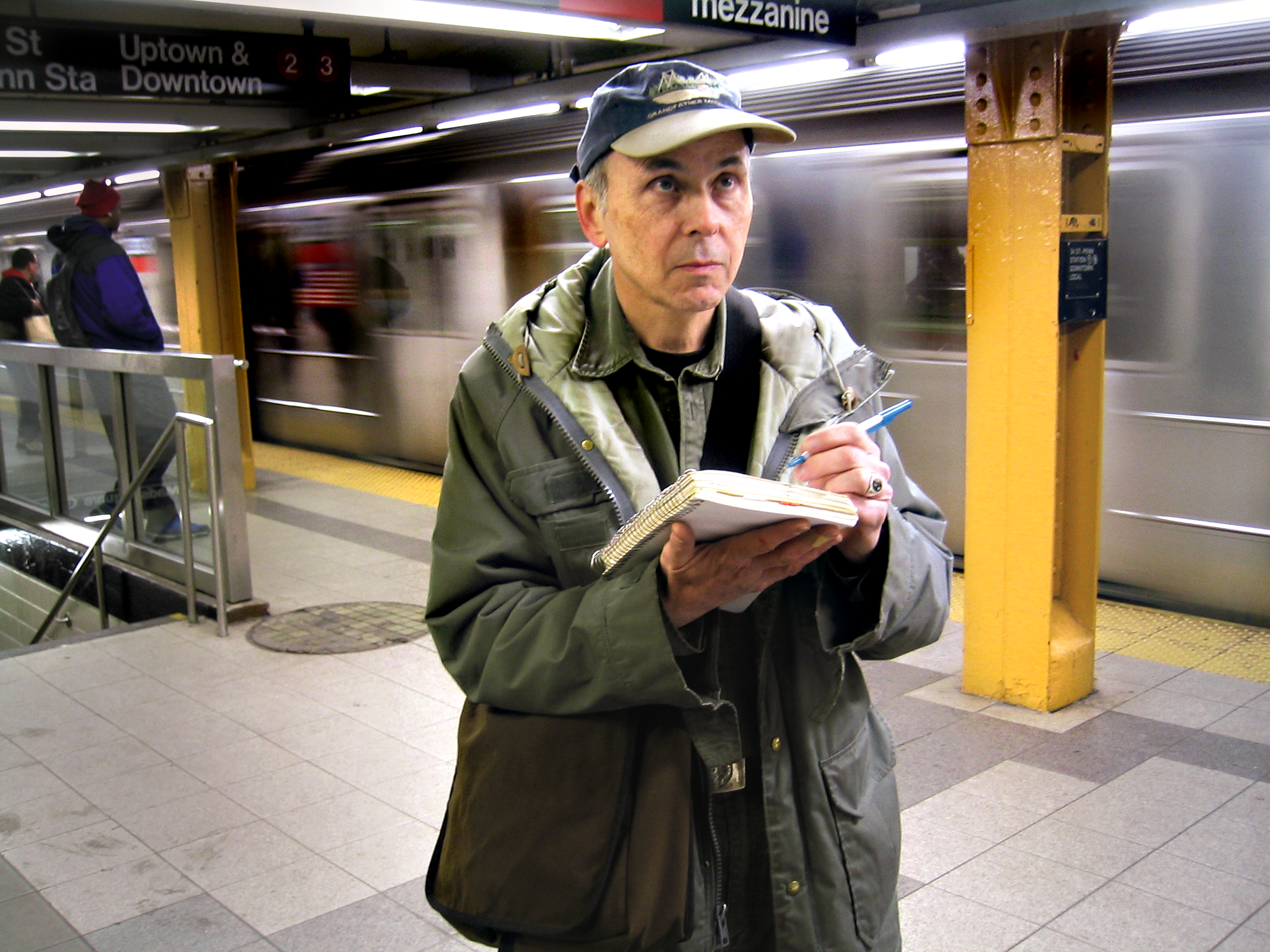 Philip Ashforth Coppola drawing in a subway station as a train goes by behind him.