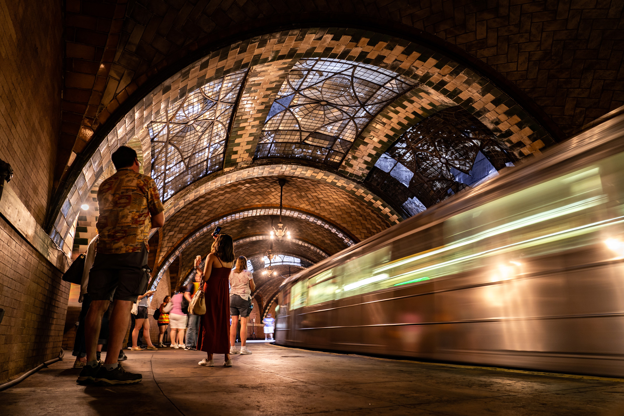 Visitors to City Hall Station look around as a 6 train passes. Photo by Chris Funfgeld.