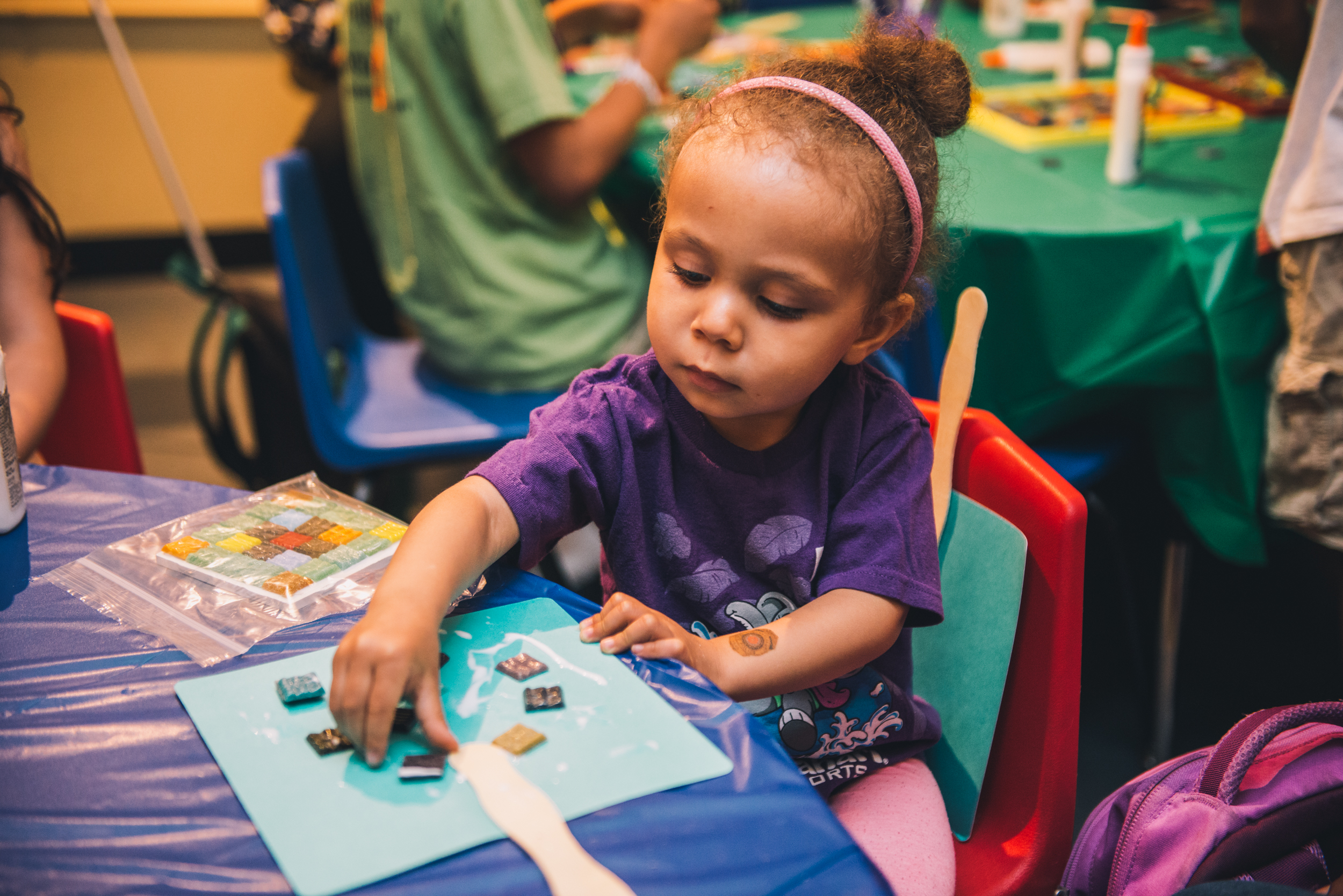 Young child sits at table and works on an art project.