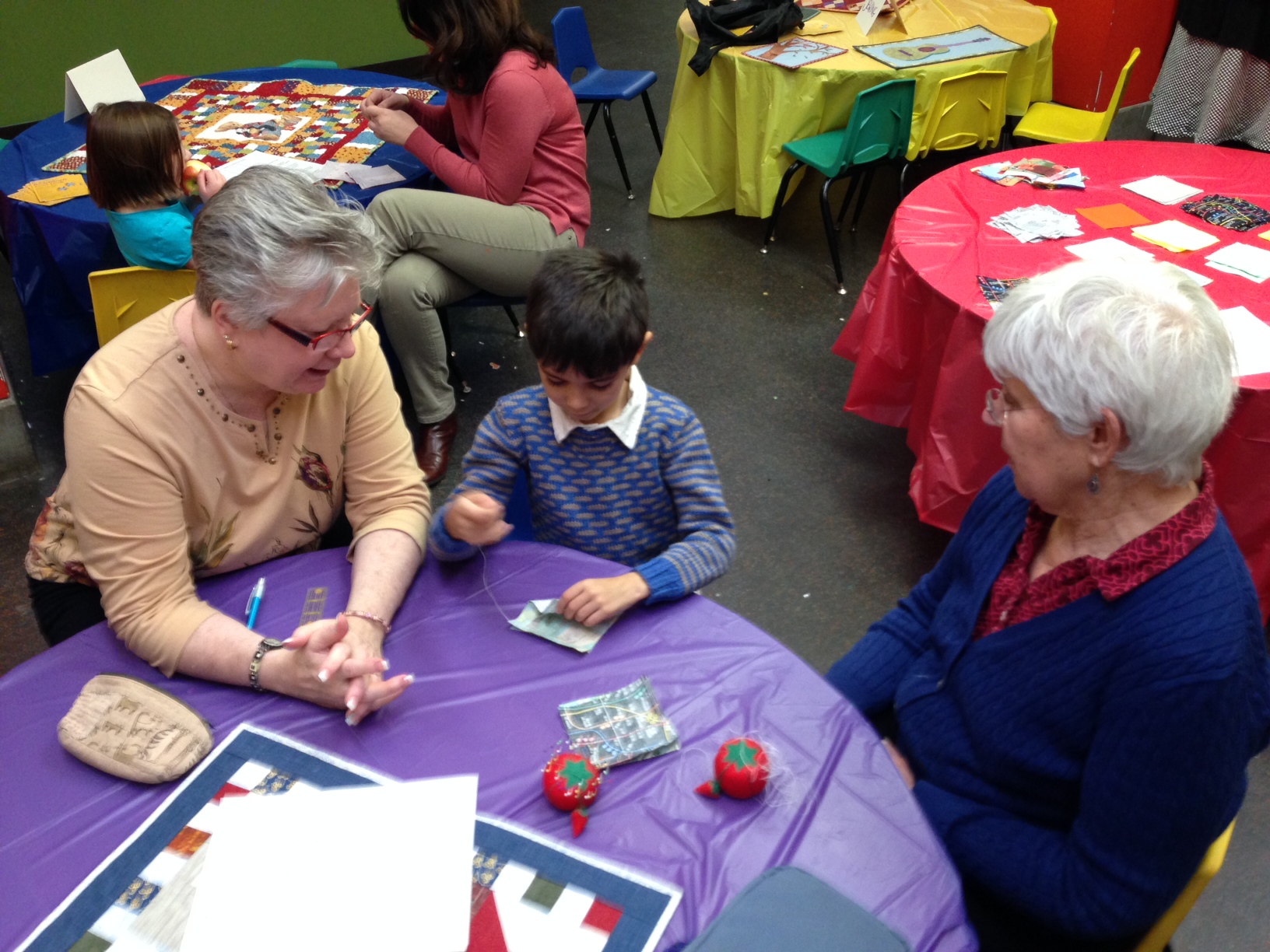 A child and two adults sit at a table and work on a project together.