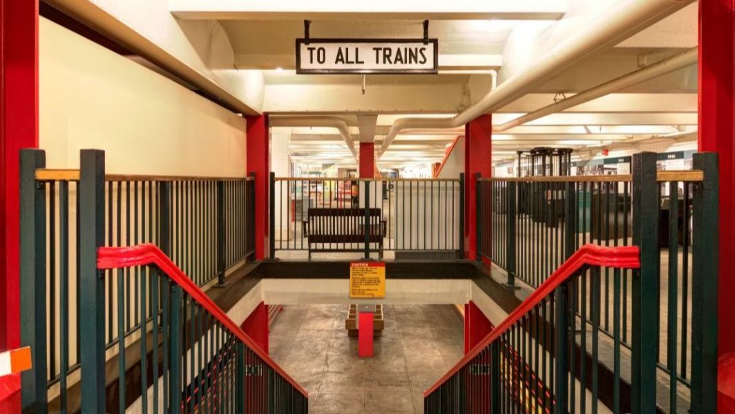 Photo of stairs to the New York Transit Museum's platform level with "To All Trains" signage; Photo by Black Paw Photo