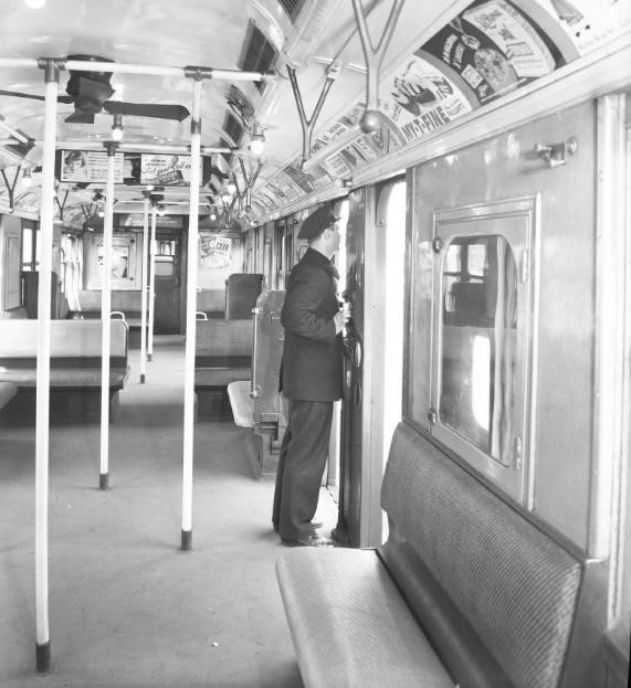 train conductor standing in the door of a 1950s BU train car