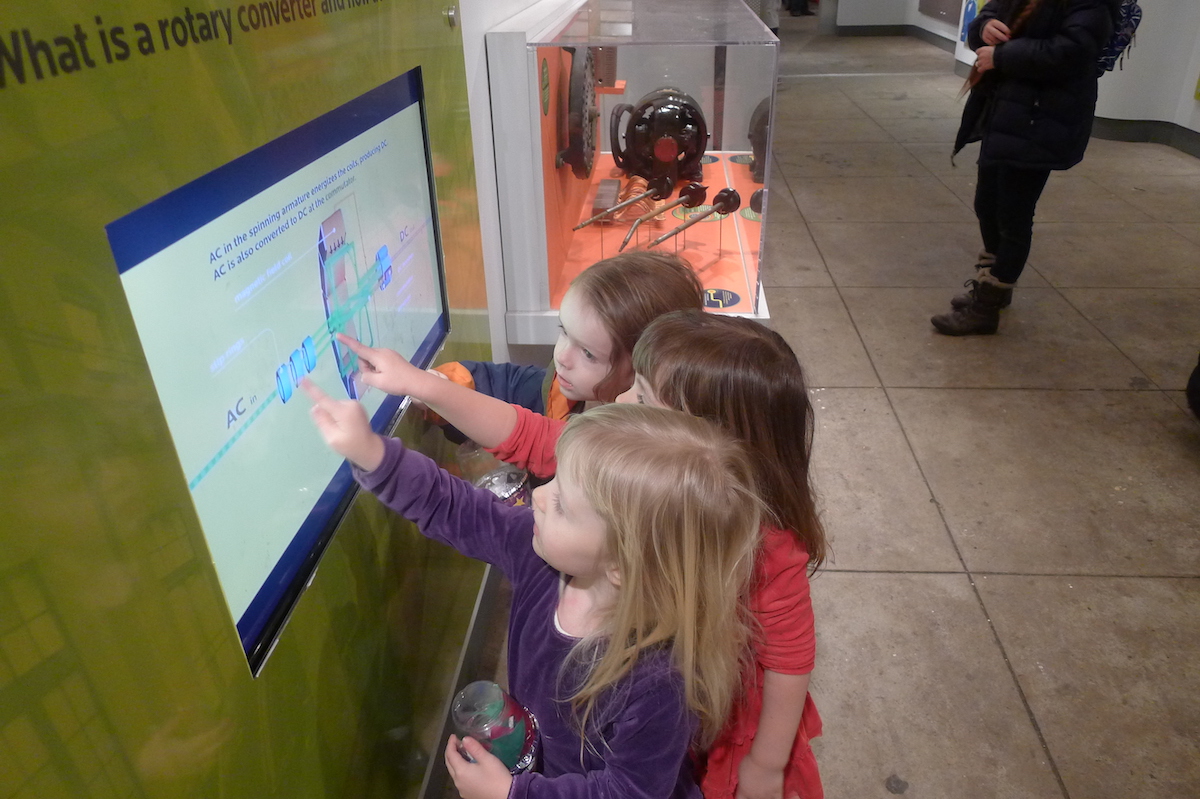 Group of children learning about electricity in interactive touchscreen in a former exhibit 