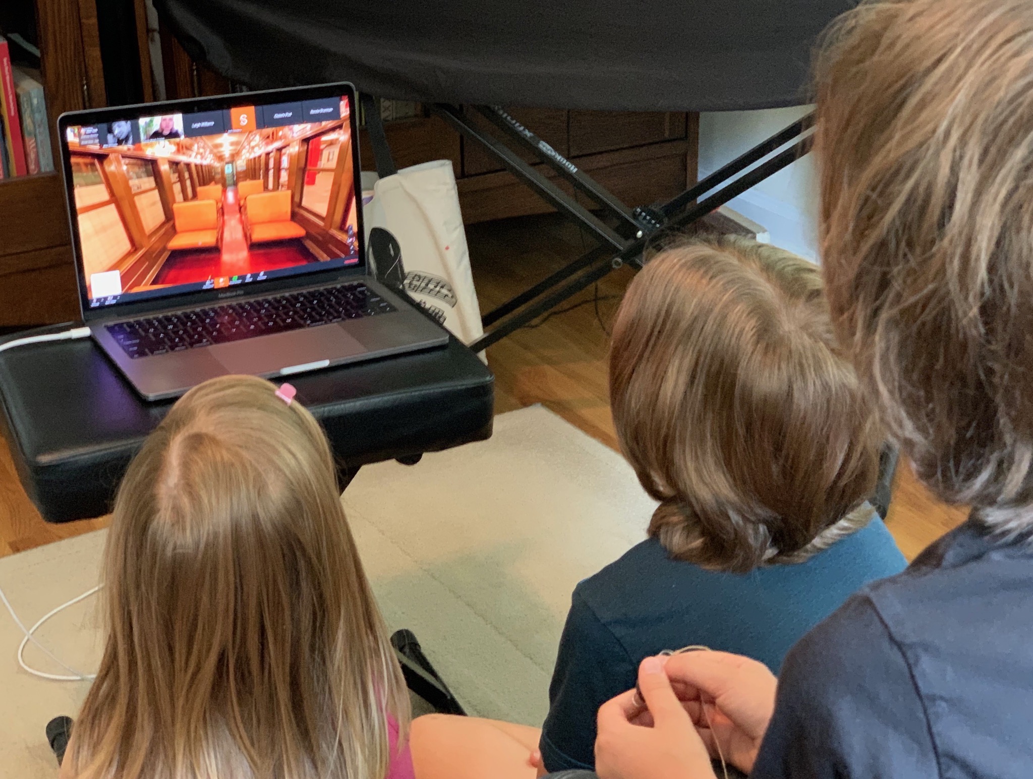 Three children sit in front of a computer displaying a train car in the Transit Museum.