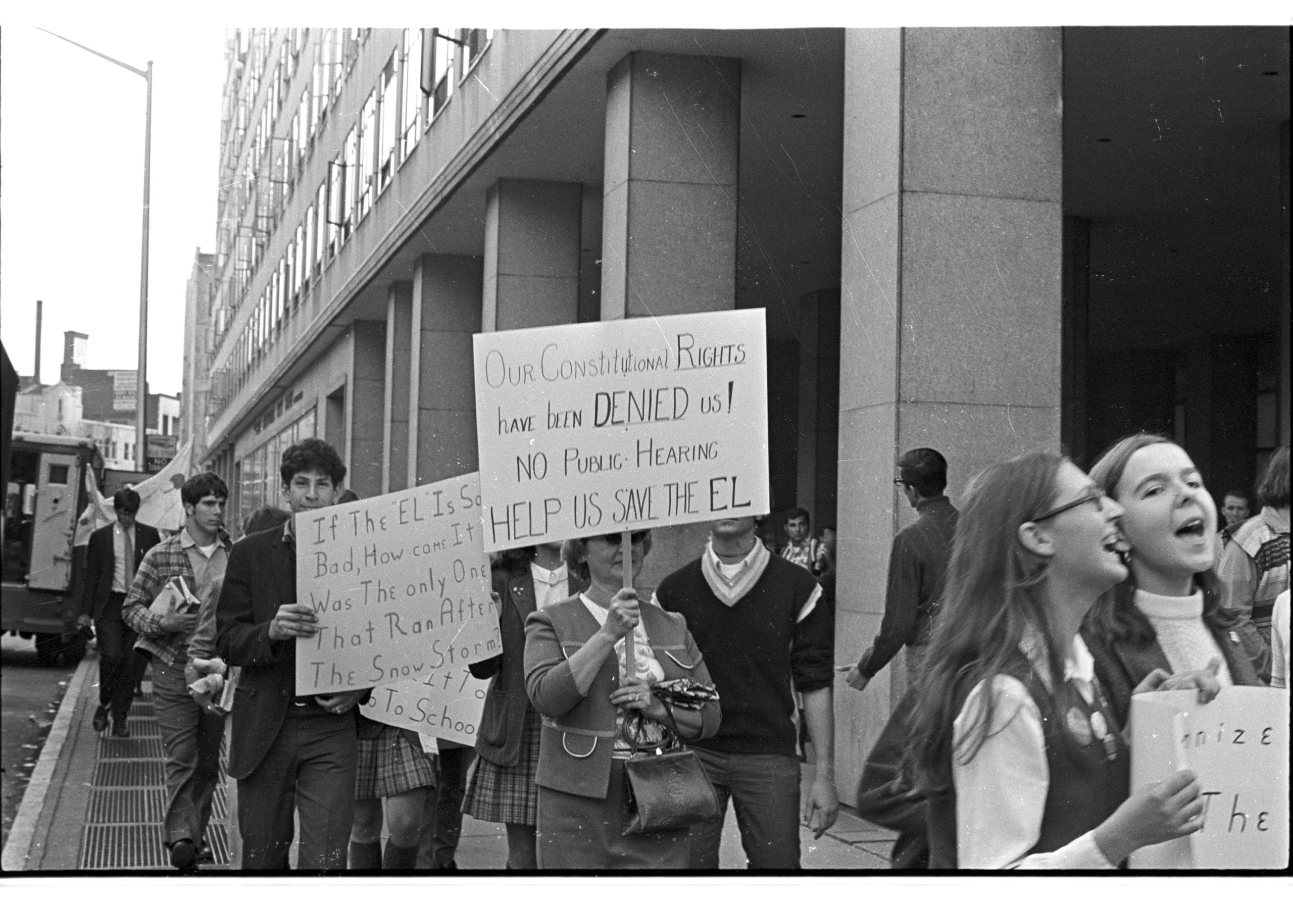 A woman holds a sign protesting the closing of the El.