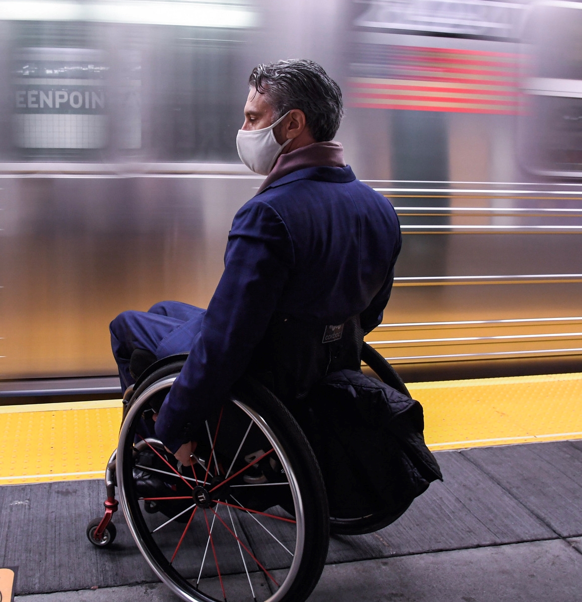Man in Wheelchair on Subway Platform in front of moving train