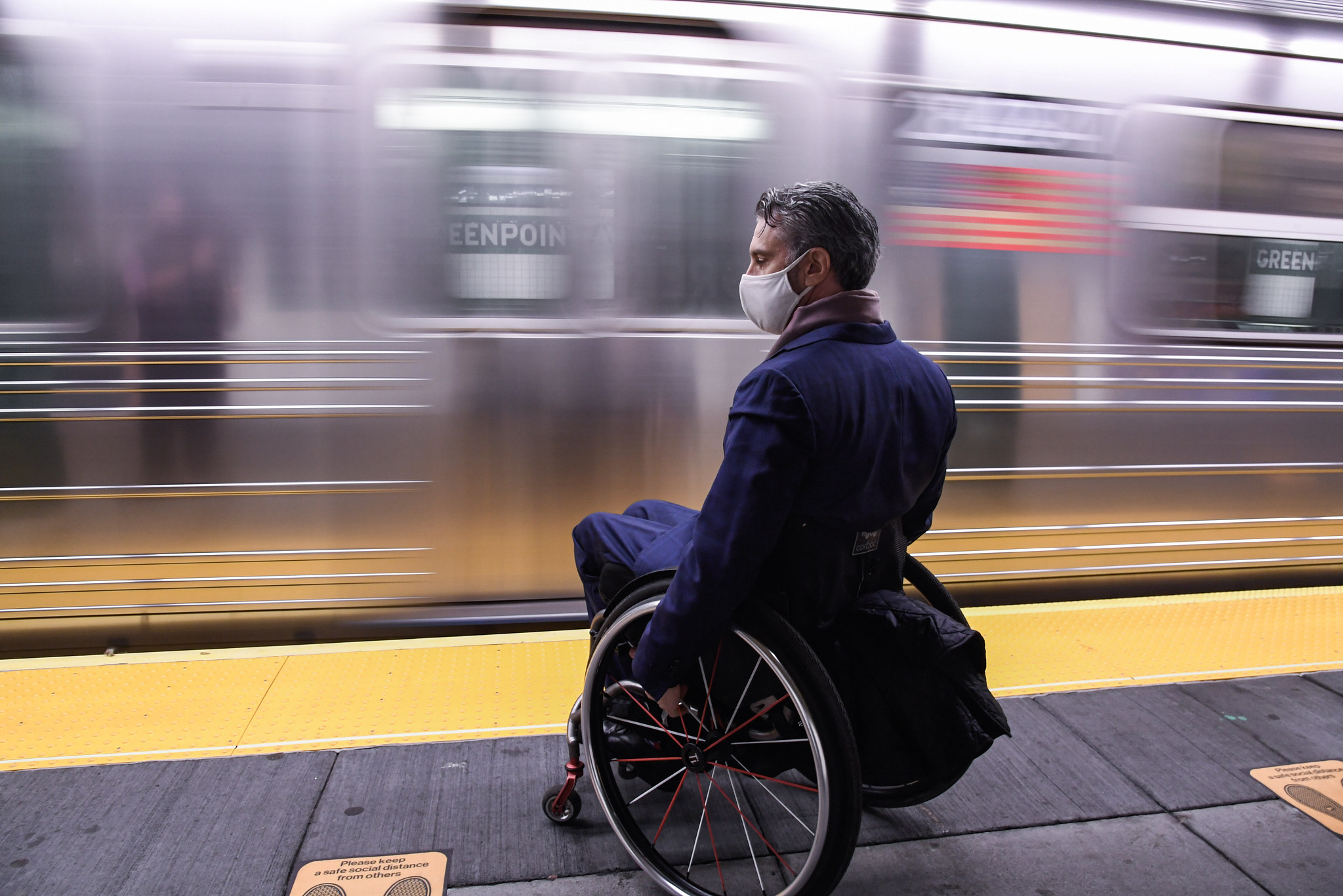 Man in Wheelcar on Platform in front of moving train
