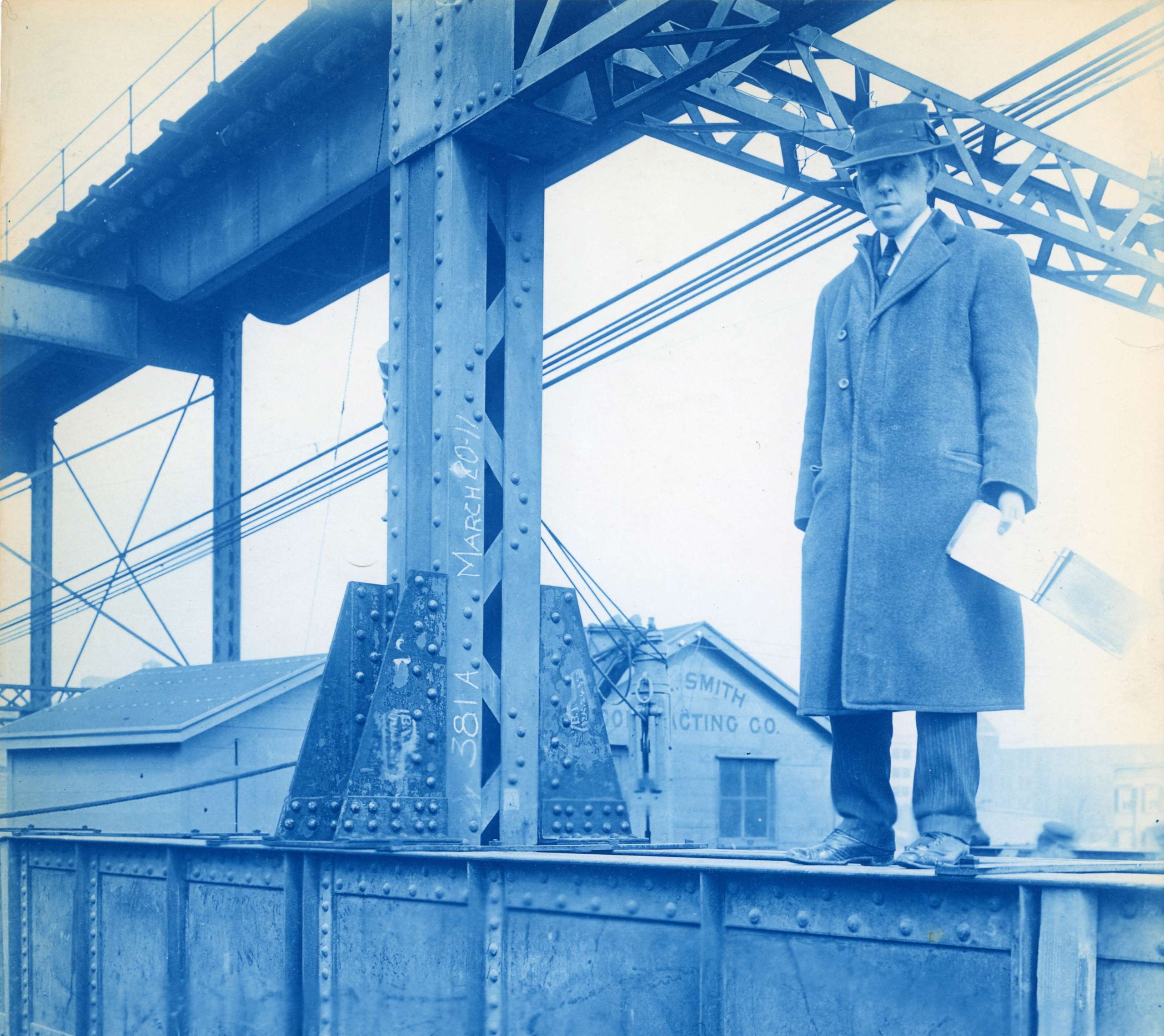 Man in suit with survey notebook stands on construction beam