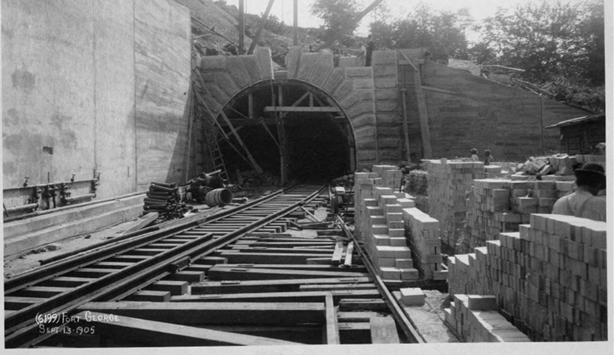 A black and white photograph of a train track leading into a tunnel.