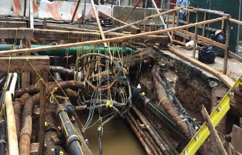 Street opening revealing conduit pipes and water