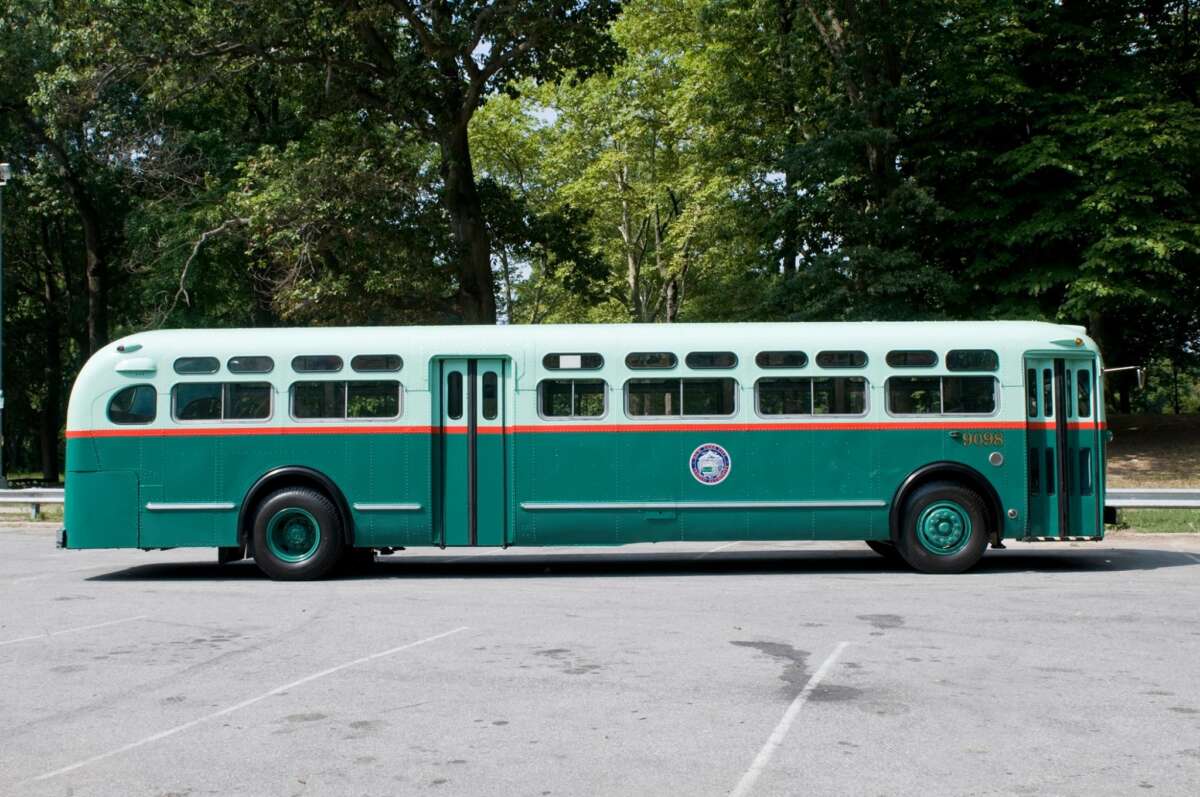 Bus #9098 in a parking lot with green trees