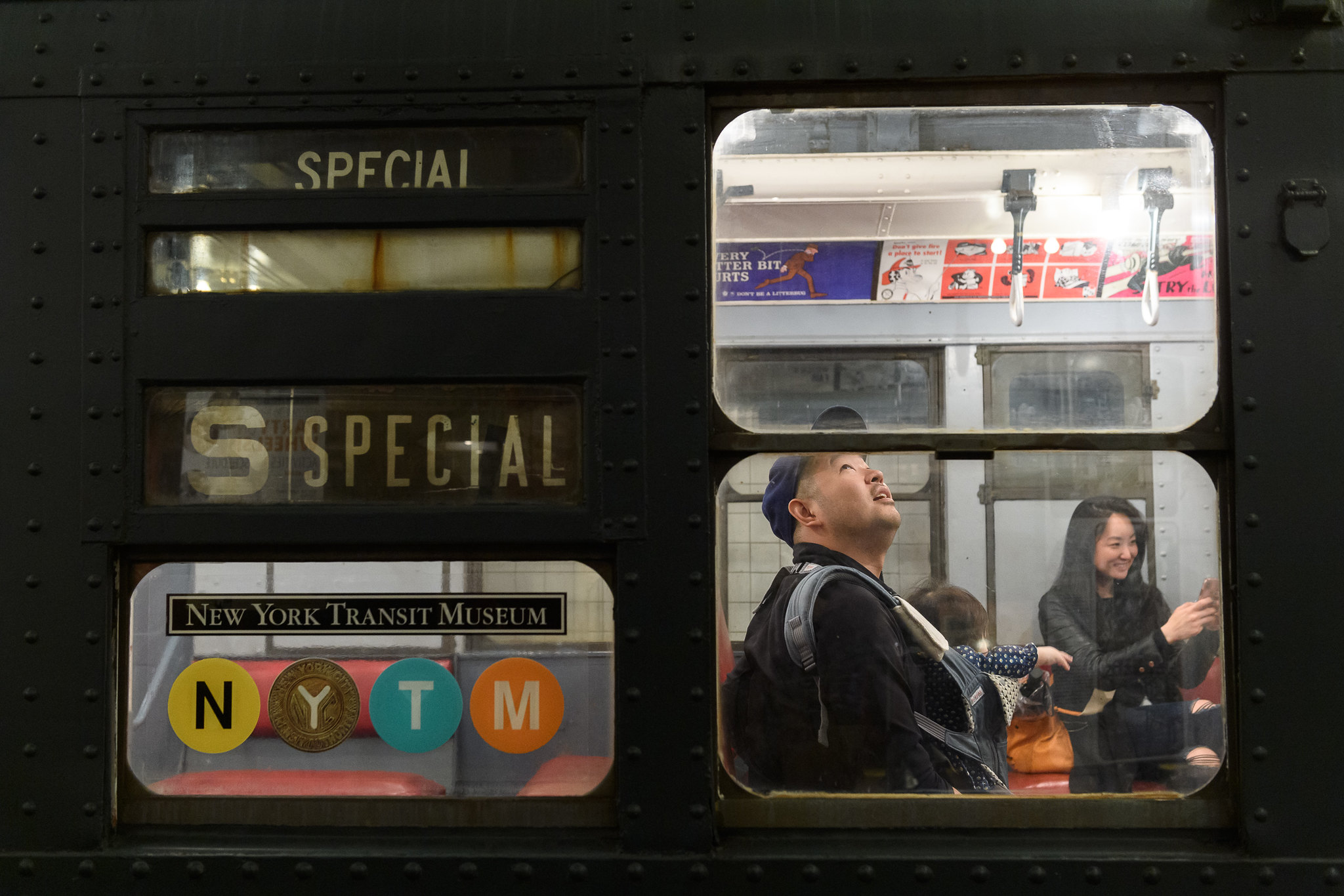 Visitors exploring vintage R1/9 car with New York Transit Museum logo in the train window