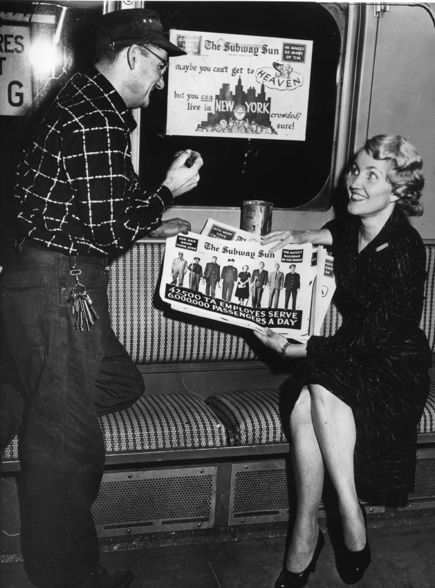 Man talking to woman holding newspaper