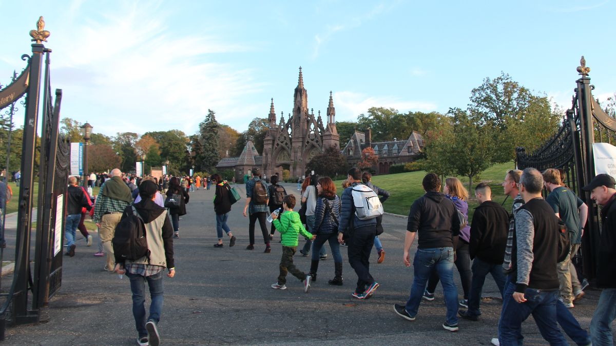 People walking through cemetery gates.