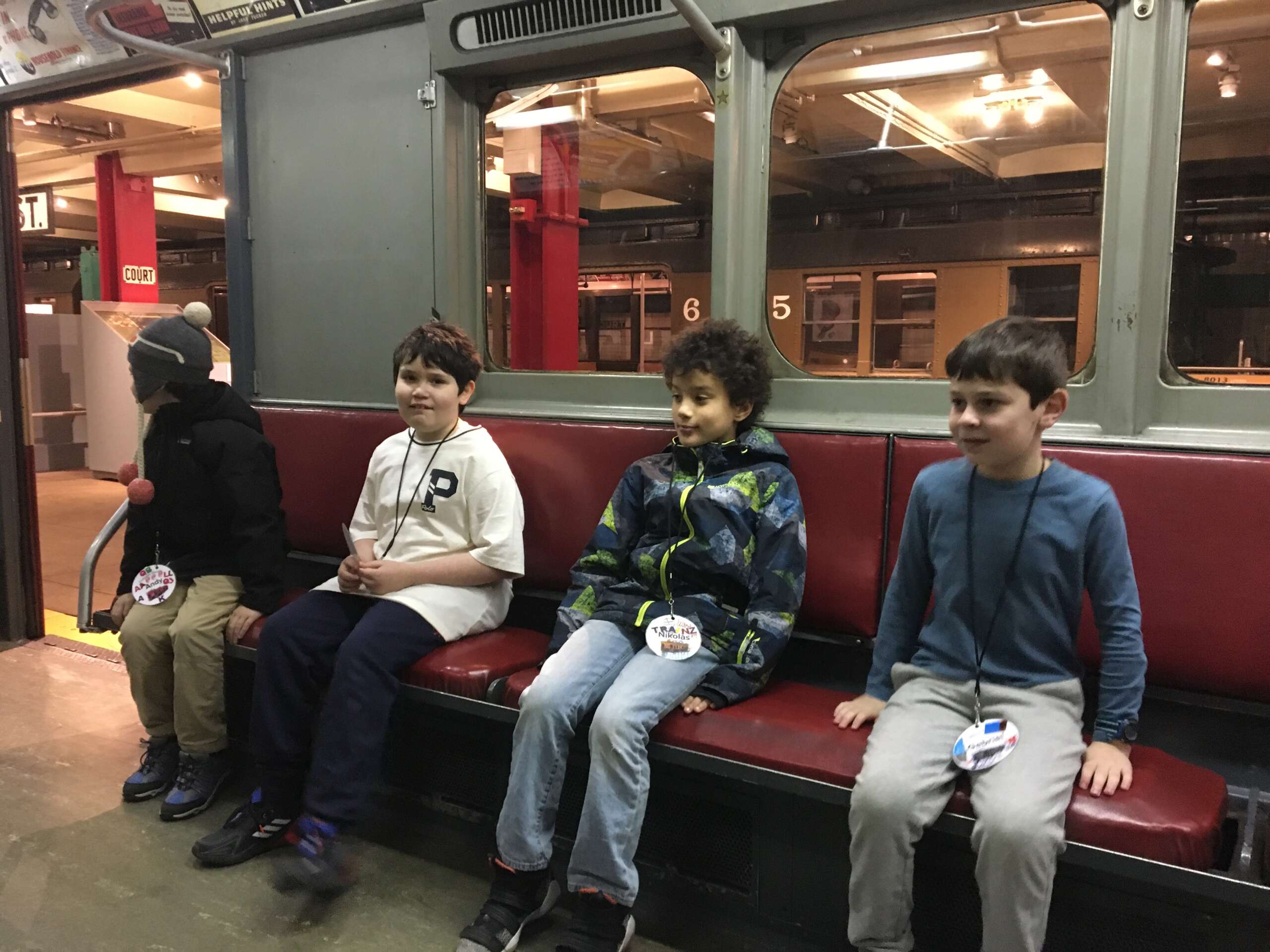 Four Subway Sleuths students sit on a vintage subway car.