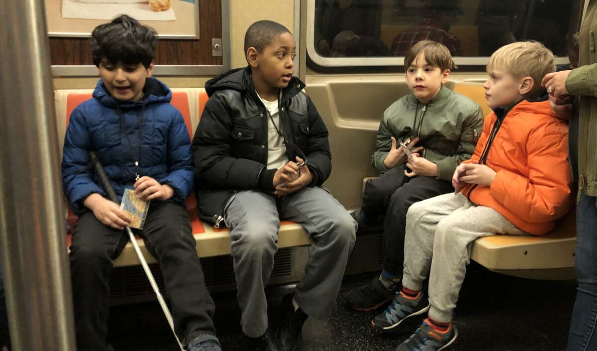 Four Subway Sleuths students sit on a subway car.