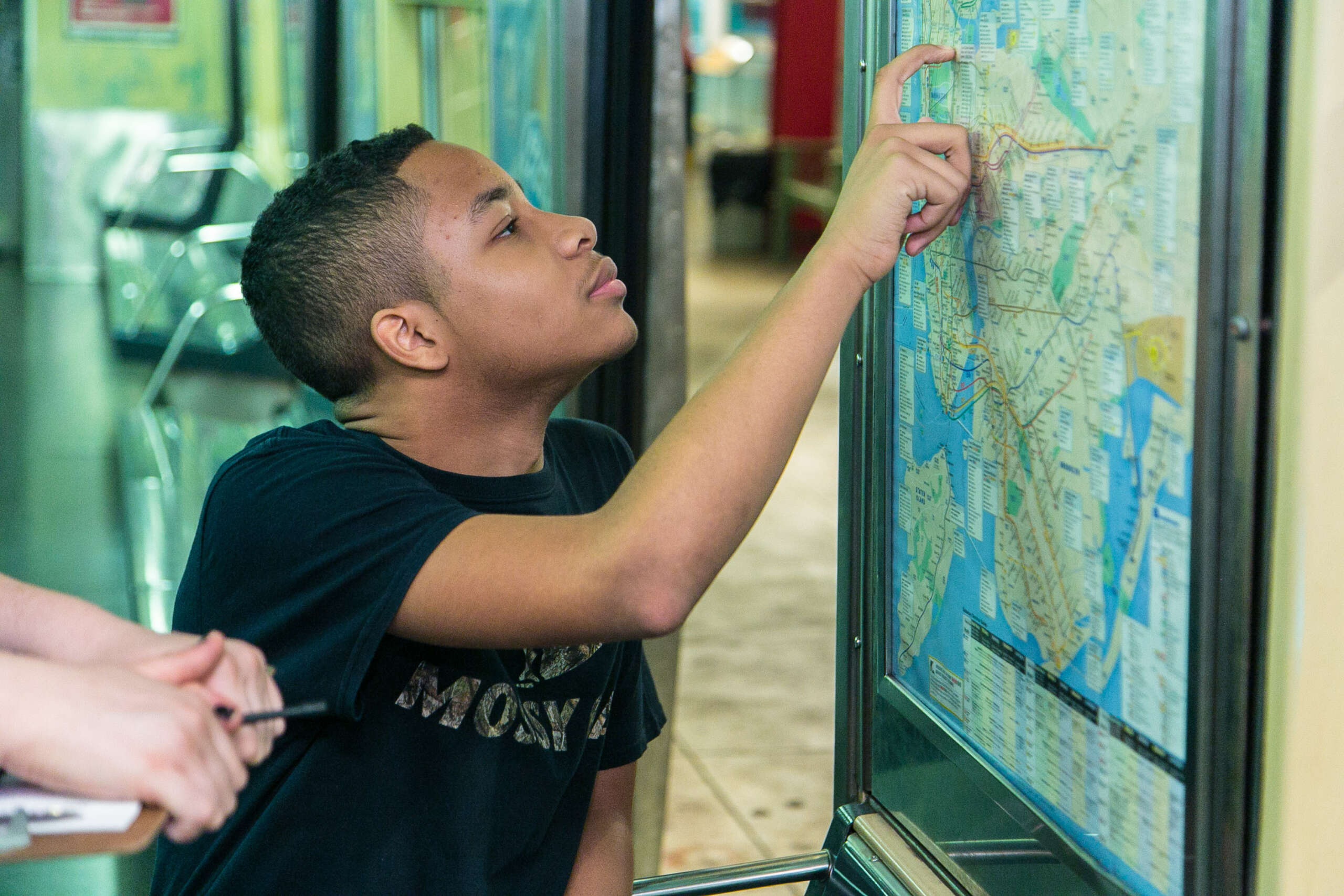A teenager traces a route on a subway map.