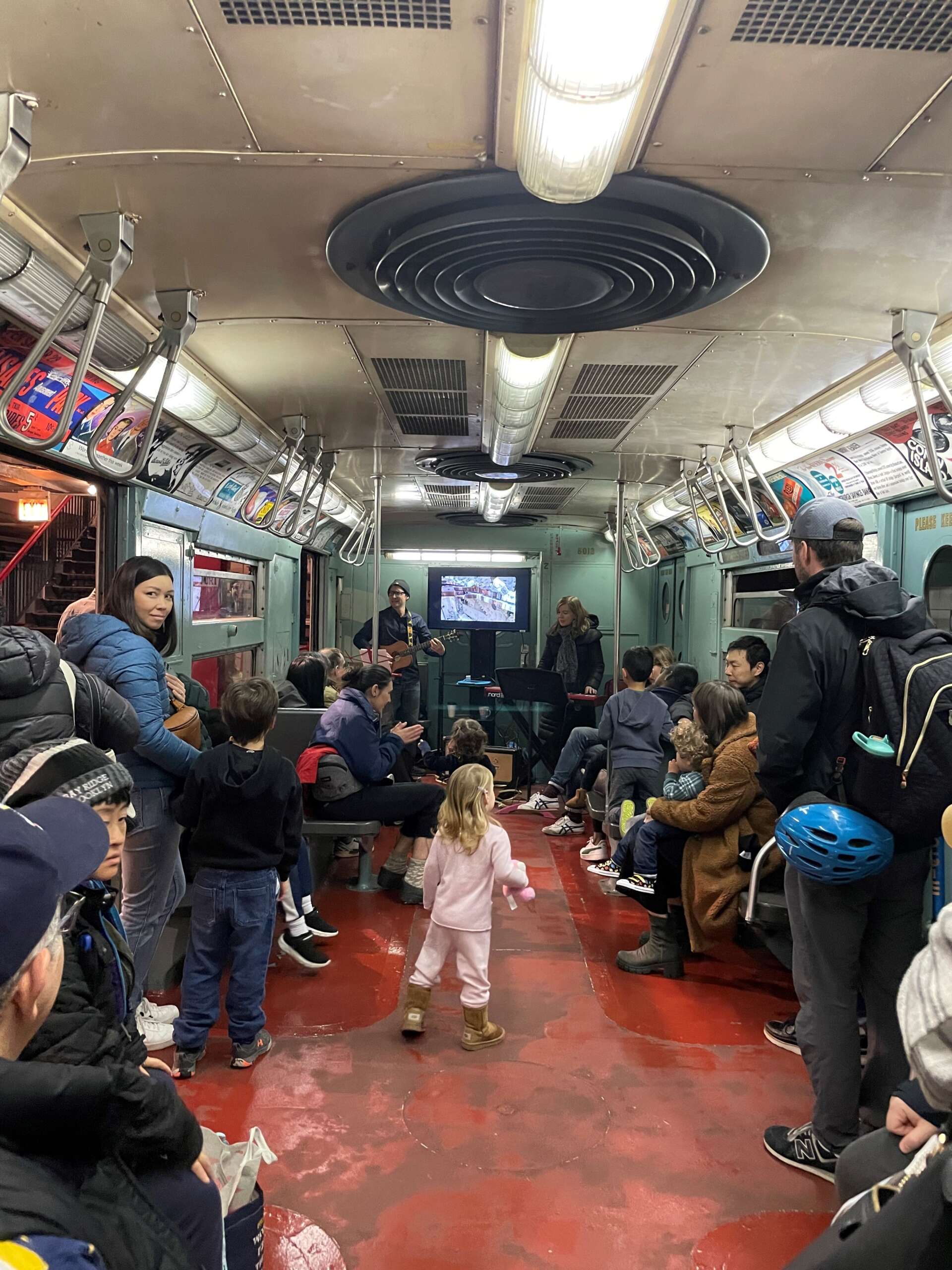 Musicians perform for families on a vintage subway car.