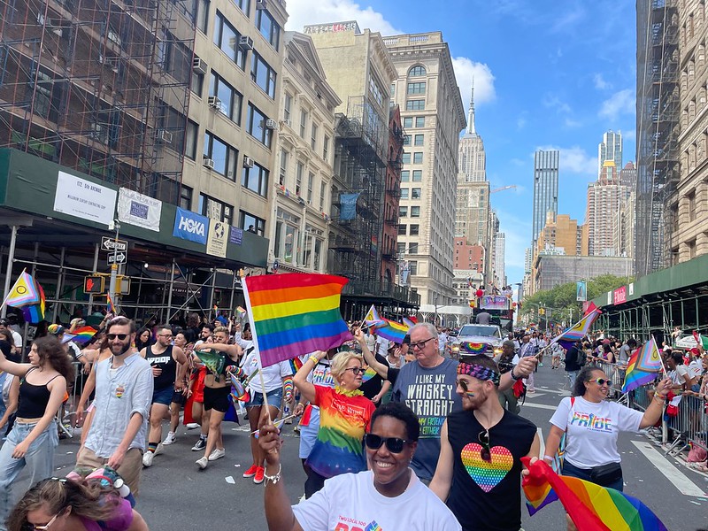 People walking on street holding rainbow flags in a New York Pride march.