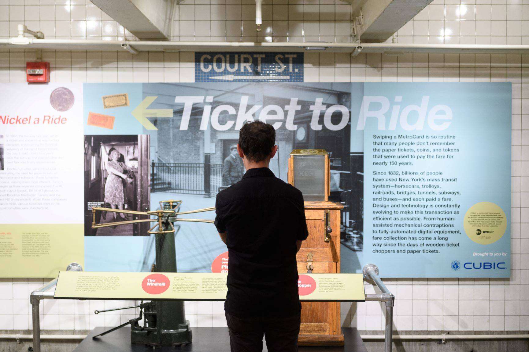 Man standing in front of ticket chopper on view in Ticket to Ride exhibit