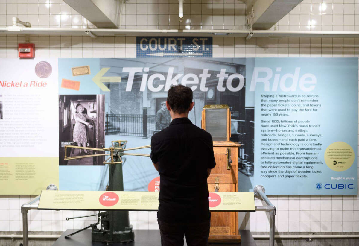 Man standing in front of ticket chopper on view in Ticket to Ride exhibit