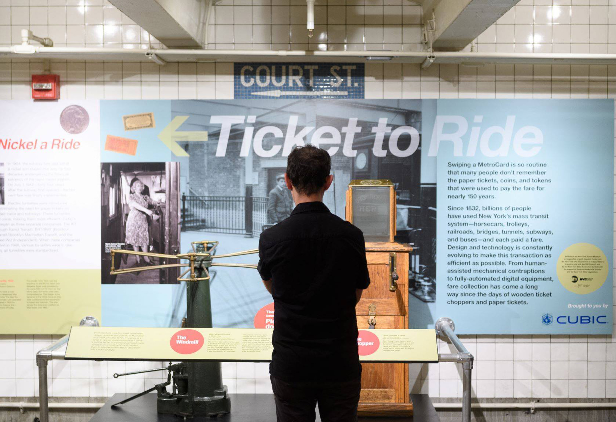 Man standing in front of ticket chopper on view in Ticket to Ride exhibit
