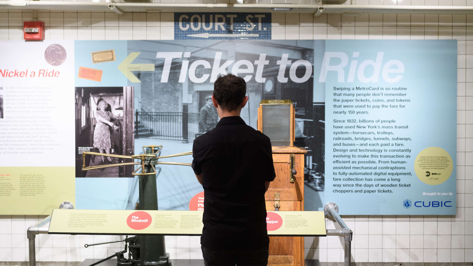 Man standing in front of ticket chopper on view in Ticket to Ride exhibit