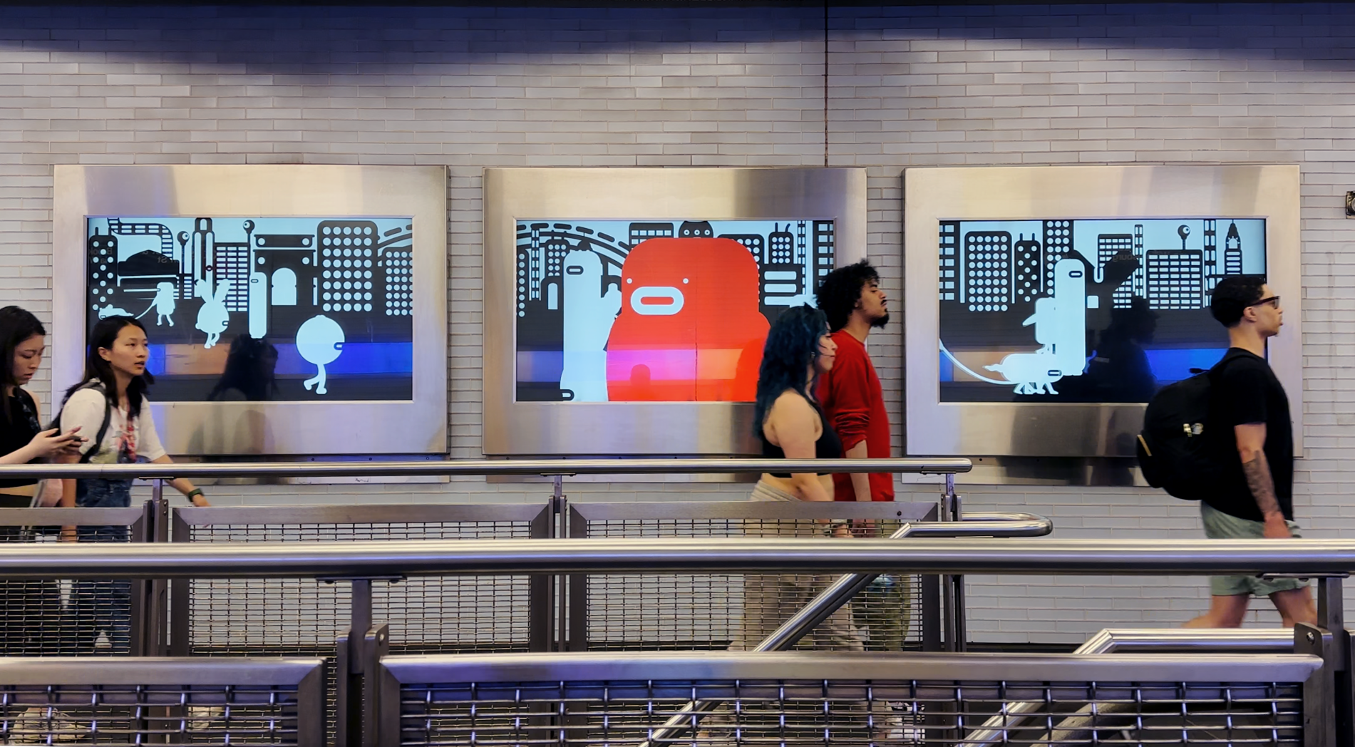 Commuters walking in front of digital art panels in the Fulton Center.