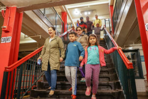 A group of children and caregivers walk down the stairs to the museum's subway platform.
