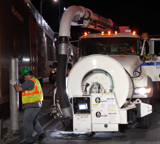 A truck with a long hose and a man holding the hose.