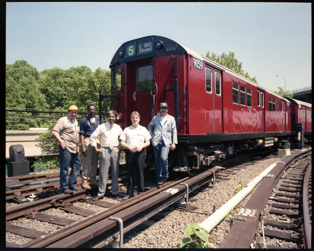 Group of men standing in front of an overhauled R-33 in the 180th Street Yard, 1991