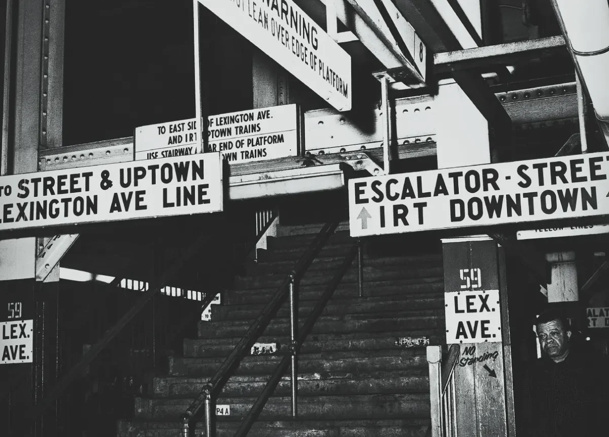 Black and white photo showing mismatch of signs in station
