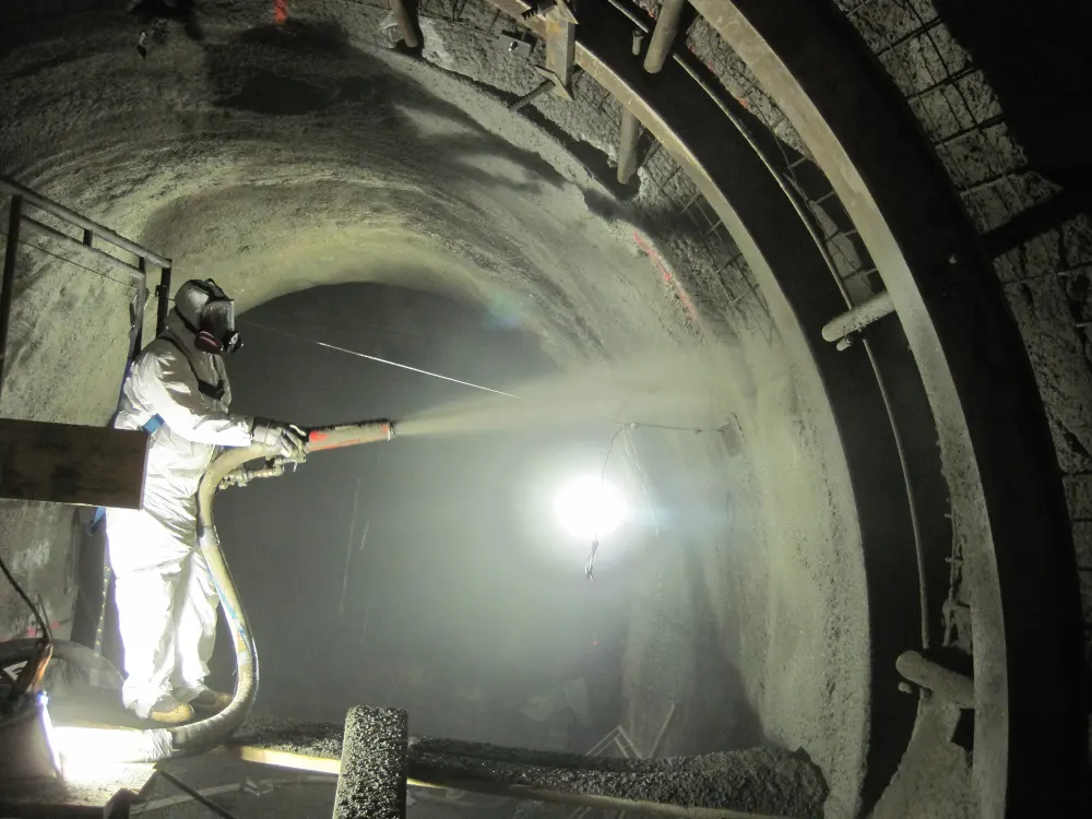Man in protective gear applying shotcrete to subway tunnel walls