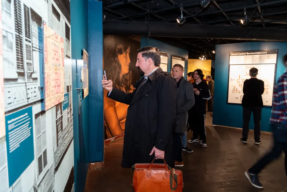 Man taking photo of pictures on the wall of a museum exhibit