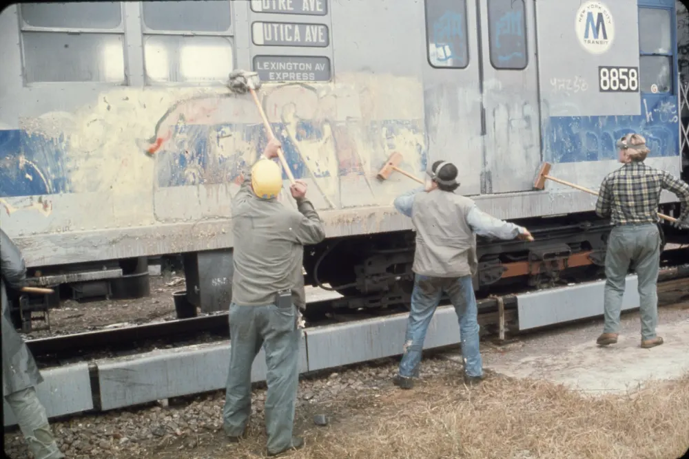 2 workers cleaning graffiti from train car