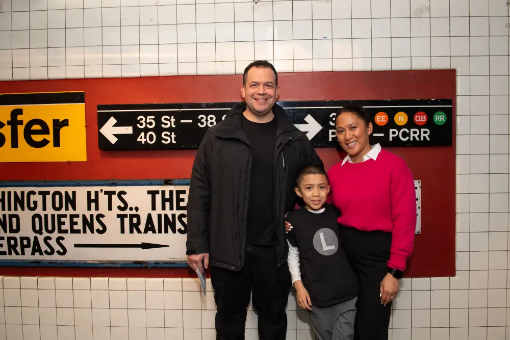 Family standing in front of subway signage