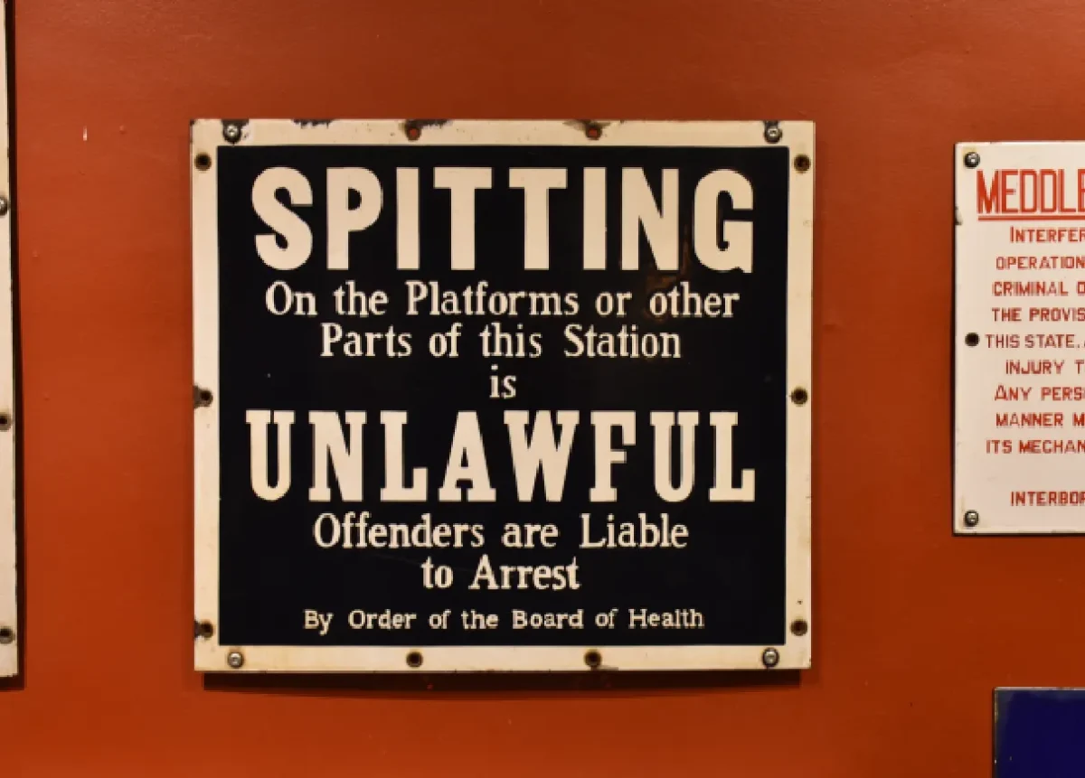 Platform etiquette signage proclaiming "Spitting is unlawful on the platform"