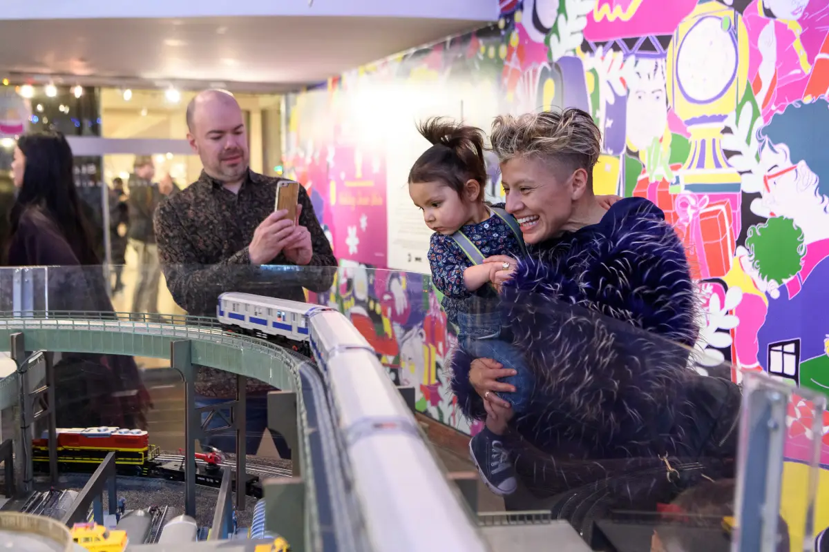 Dad takes photo of mom and daughter looking at the Holiday Train Show
