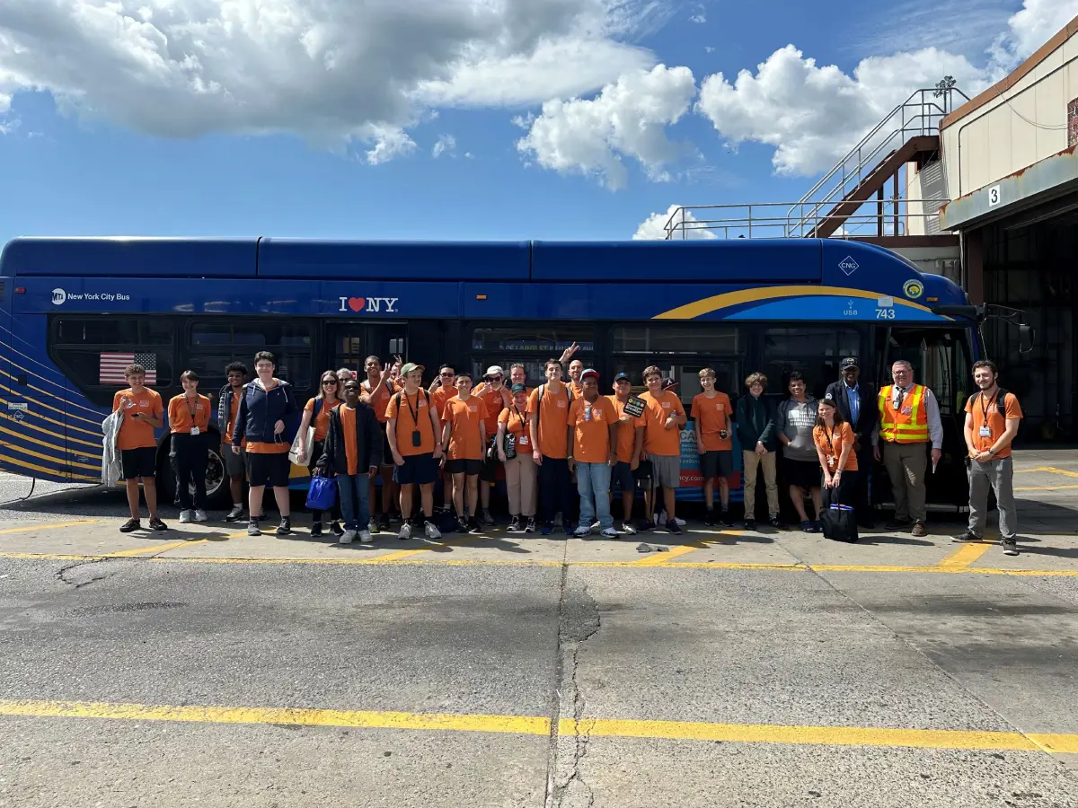 Transit Quest teens stand in front of a bus on a tour of the Jackie Gleason Bus Depot