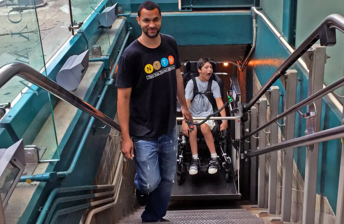 Museum staff member assists child with using the wheel chair lift at the museum in Brooklyn