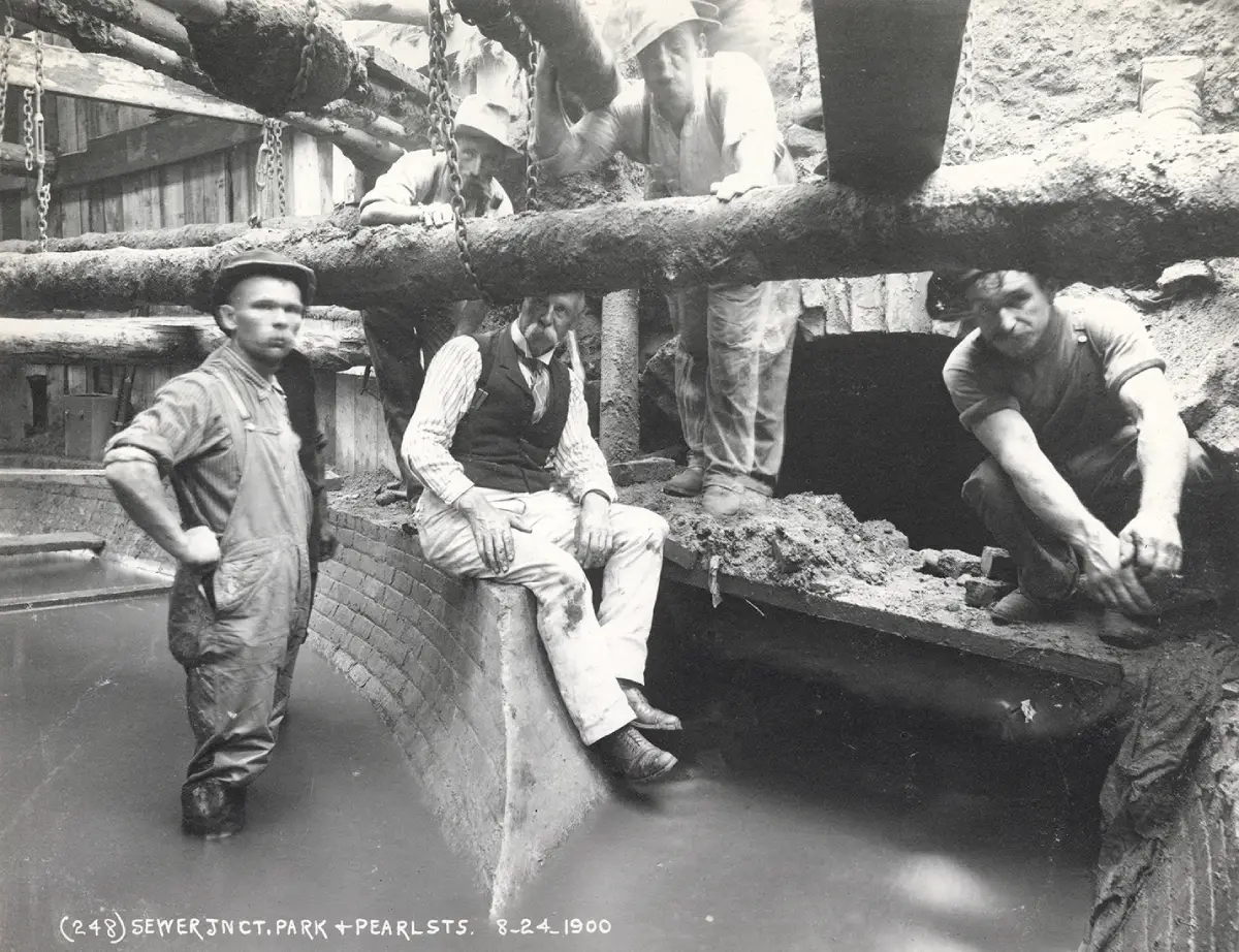 Tunnel workers sitting and standing under sewer pipes during subway contruction