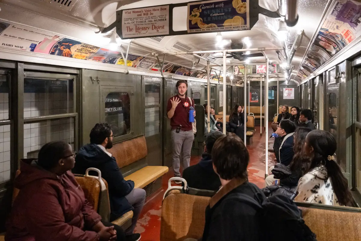 Tour guide speaking to group inside a vintage train car