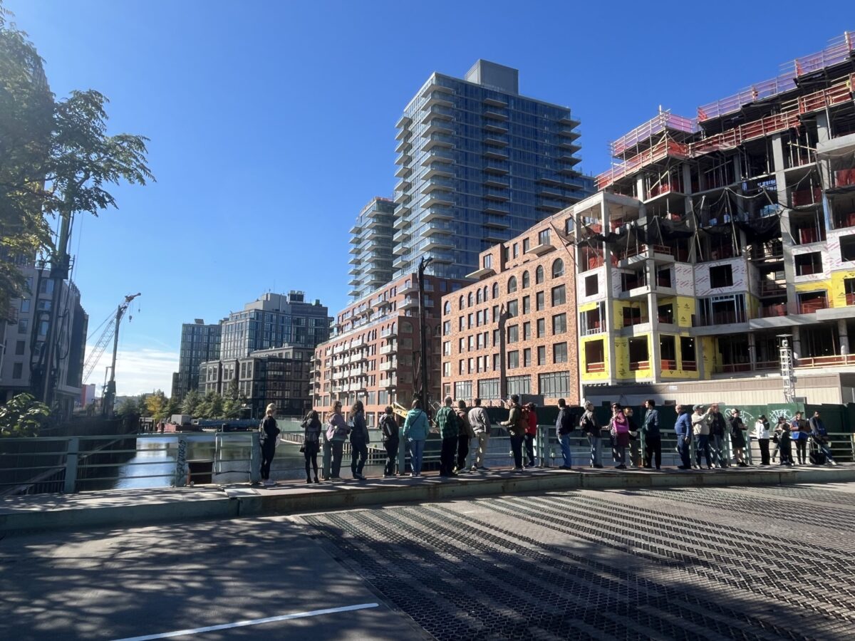Tour group stands on bridge street over canal.