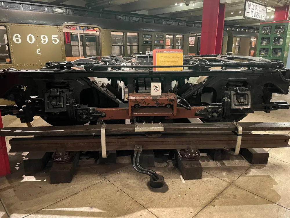 Motor truck on display on the museum's platform, vintage train car seen in the background