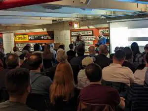 Seated participants listen to a lecture in the New York Transit Museum's sign gallery.