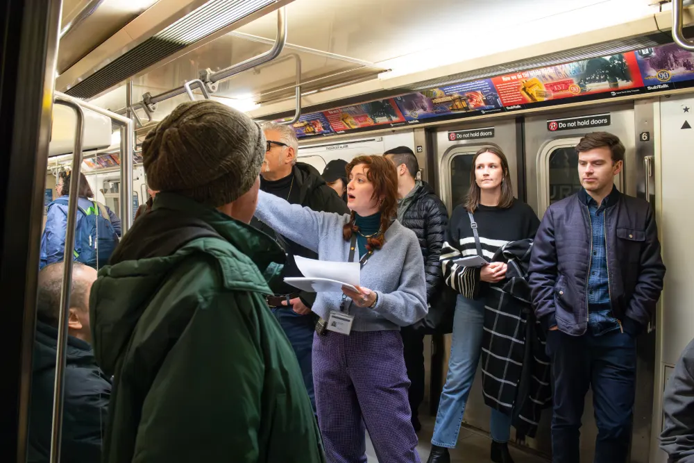 Museum educator leading a tour group through a vintage train car at the museum