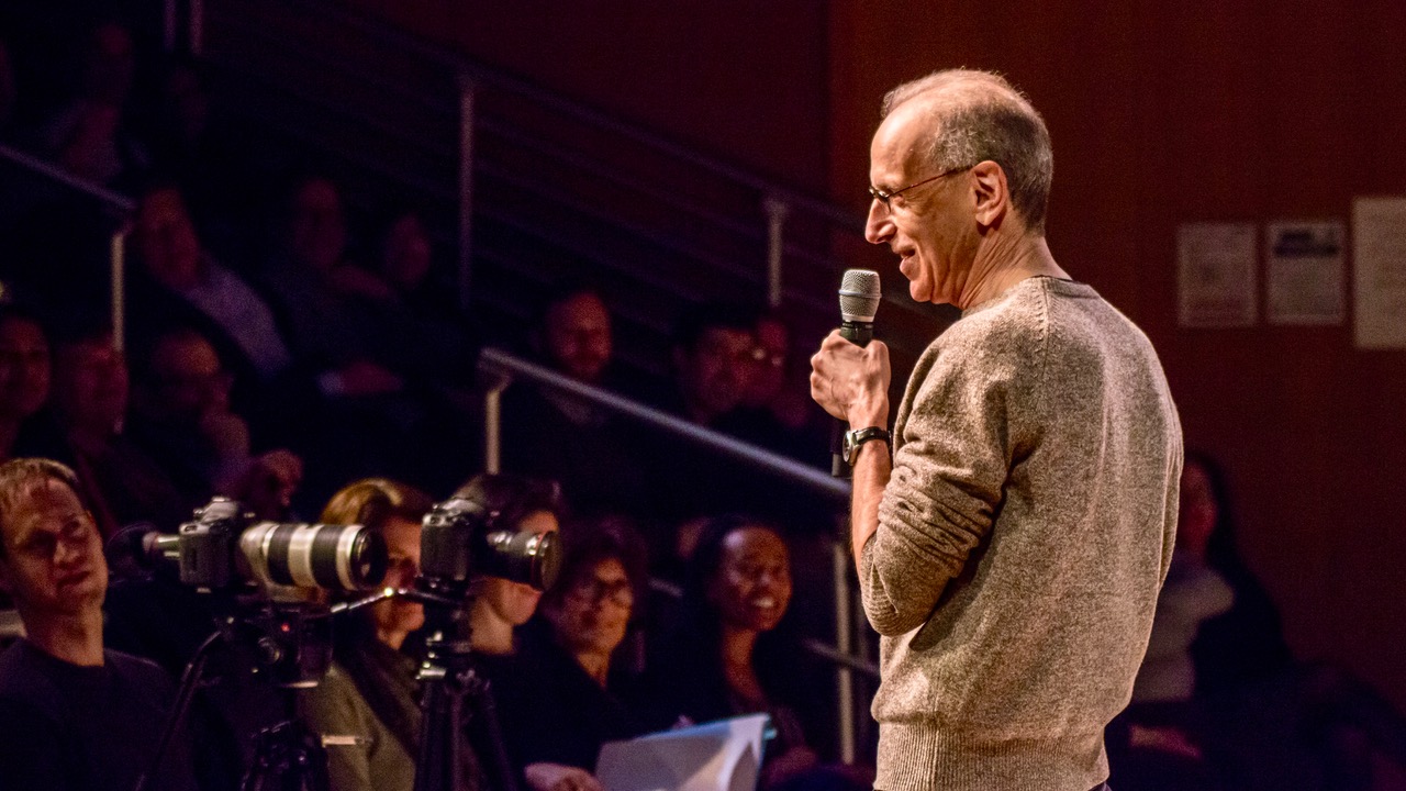 A man on a microphone talks to an audience.